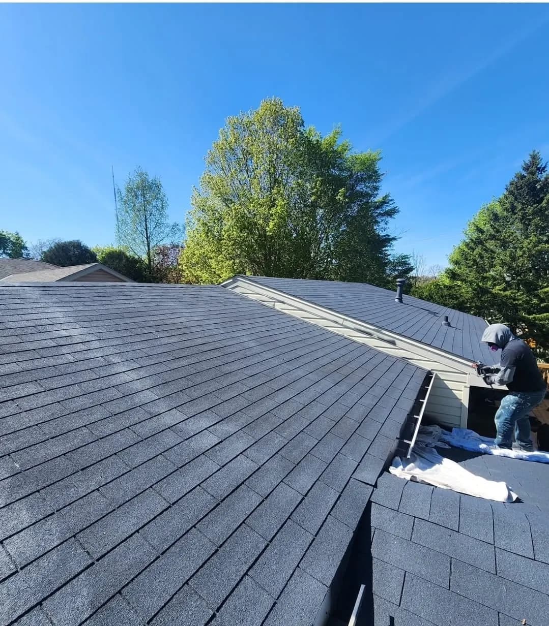 Crew member applying a coating to an asphalt shingle roof