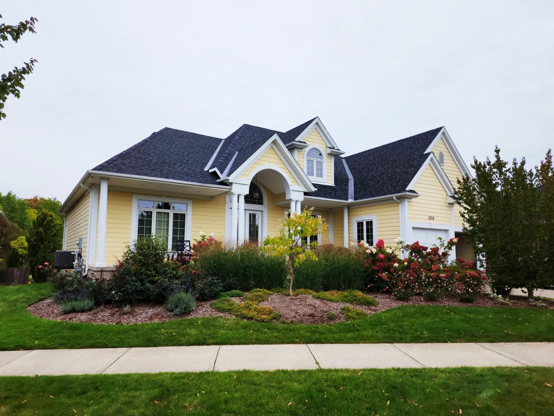 Yellow house with white trim and a landscaped front garden